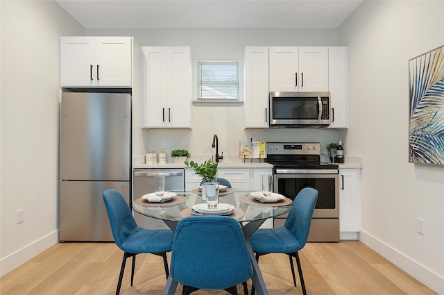 kitchen featuring appliances with stainless steel finishes, white cabinets, and light wood-type flooring