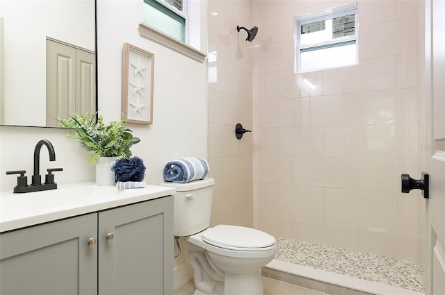 bathroom with vanity, tiled shower, and toilet