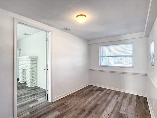 spare room with wood-type flooring and a fireplace