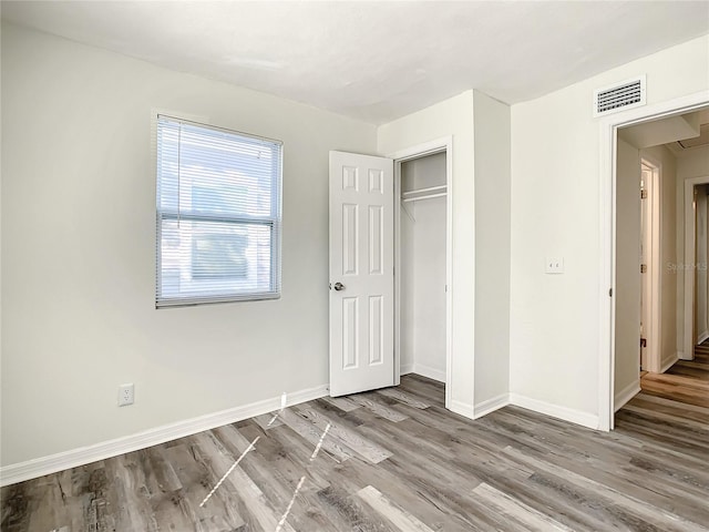 unfurnished bedroom with hardwood / wood-style floors and a closet