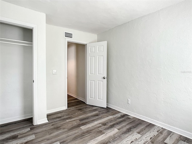 unfurnished bedroom featuring dark hardwood / wood-style flooring and a closet