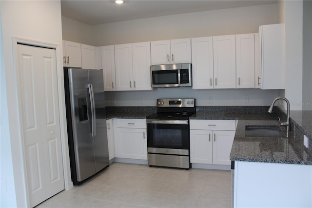 kitchen featuring appliances with stainless steel finishes, sink, dark stone counters, and white cabinets