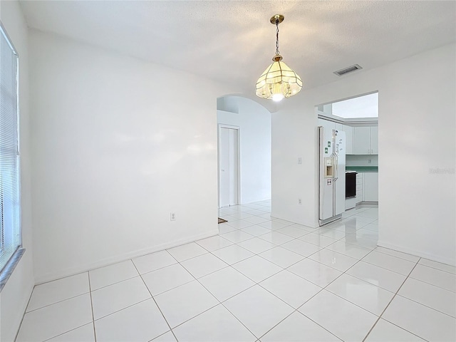 spare room featuring light tile patterned floors and a textured ceiling