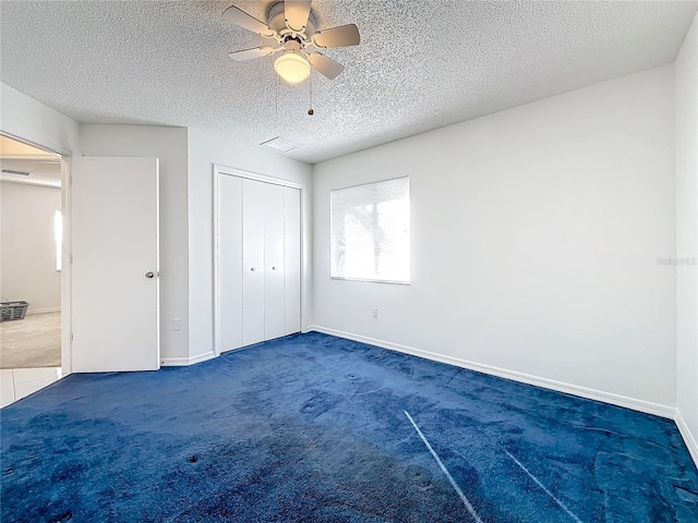 unfurnished bedroom featuring ceiling fan, a closet, a textured ceiling, and dark colored carpet