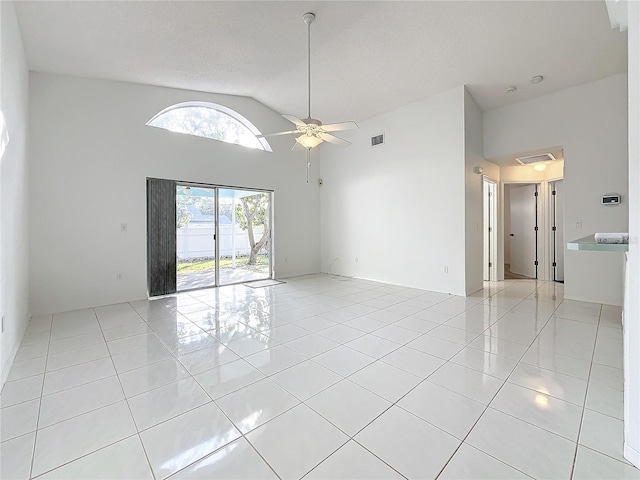 tiled spare room with ceiling fan and high vaulted ceiling