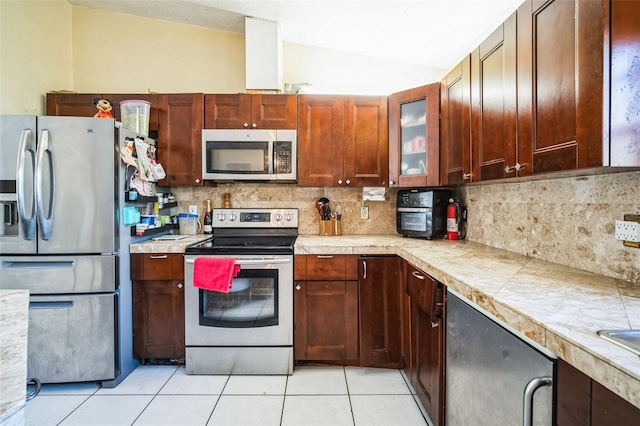 kitchen with tasteful backsplash, light tile patterned floors, lofted ceiling, and stainless steel appliances