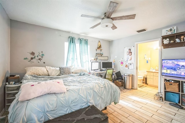 bedroom with ceiling fan, a textured ceiling, light hardwood / wood-style flooring, and ensuite bath