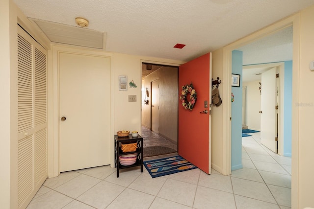 corridor featuring light tile patterned floors and a textured ceiling