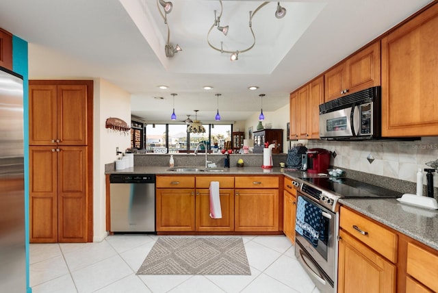 kitchen featuring sink, hanging light fixtures, stainless steel appliances, kitchen peninsula, and a raised ceiling