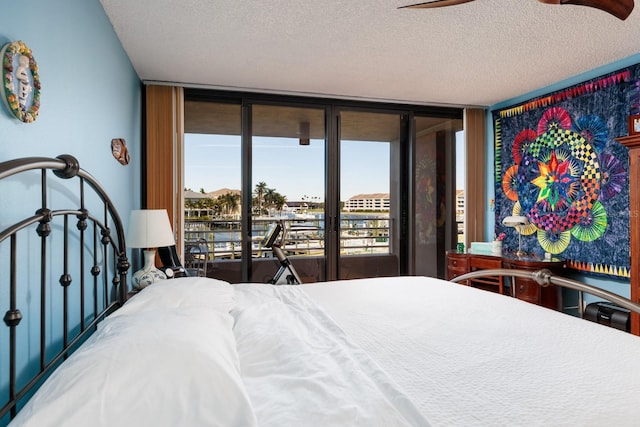 bedroom with access to exterior, expansive windows, and a textured ceiling