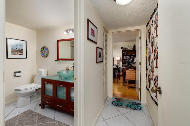 bathroom with vanity, a textured ceiling, tile patterned floors, and toilet