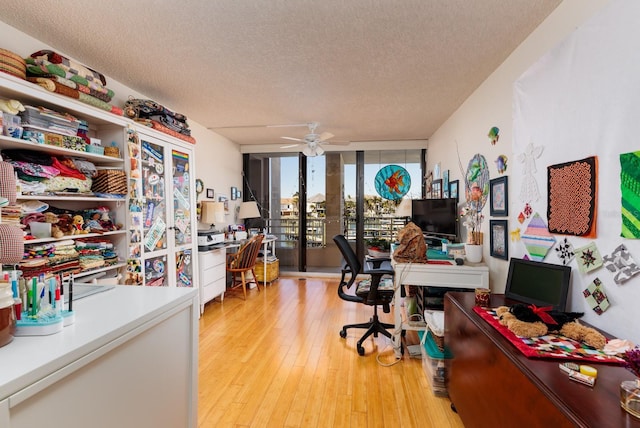 home office with ceiling fan, light hardwood / wood-style flooring, floor to ceiling windows, and a textured ceiling