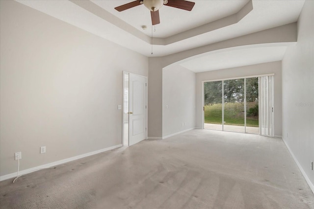 spare room with light colored carpet, ceiling fan, and a tray ceiling