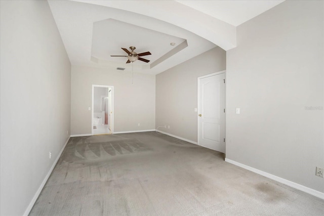 carpeted empty room featuring a raised ceiling and ceiling fan