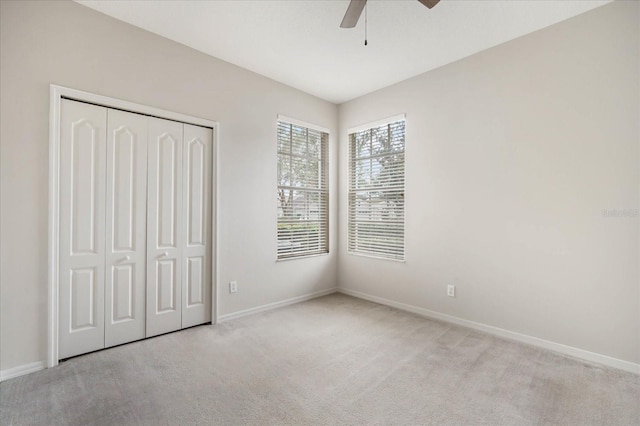 unfurnished bedroom featuring light colored carpet, ceiling fan, and a closet