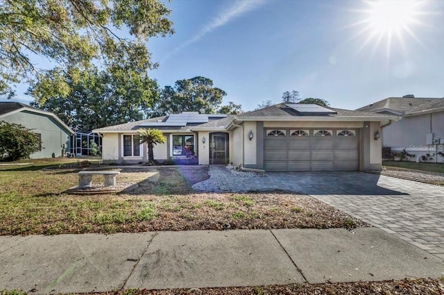 ranch-style home featuring a garage, a front yard, and solar panels