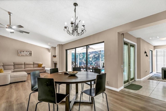 dining room with hardwood / wood-style floors, ceiling fan with notable chandelier, and a textured ceiling