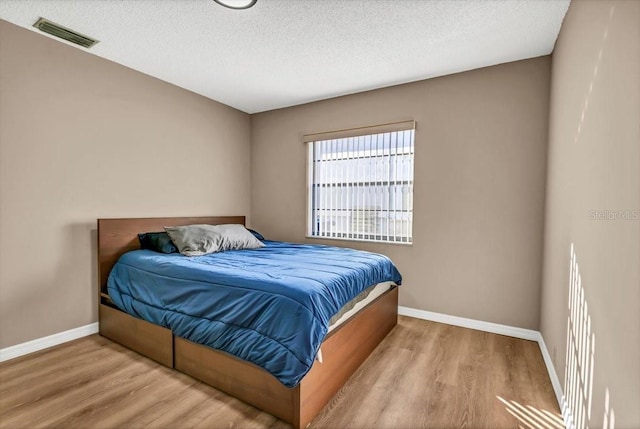 bedroom with light hardwood / wood-style floors and a textured ceiling