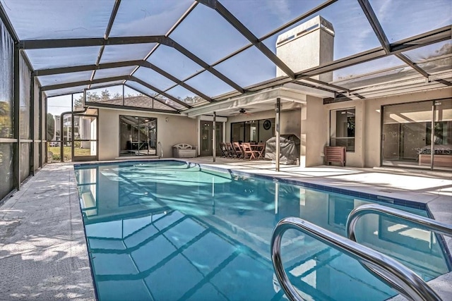 view of swimming pool with ceiling fan, a lanai, and a patio