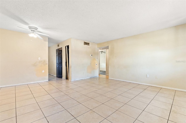 empty room with ceiling fan, a textured ceiling, and light tile patterned floors