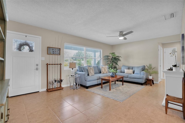 living room with ceiling fan, a textured ceiling, and light tile patterned flooring