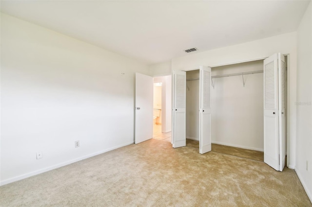 unfurnished bedroom with light colored carpet and a closet