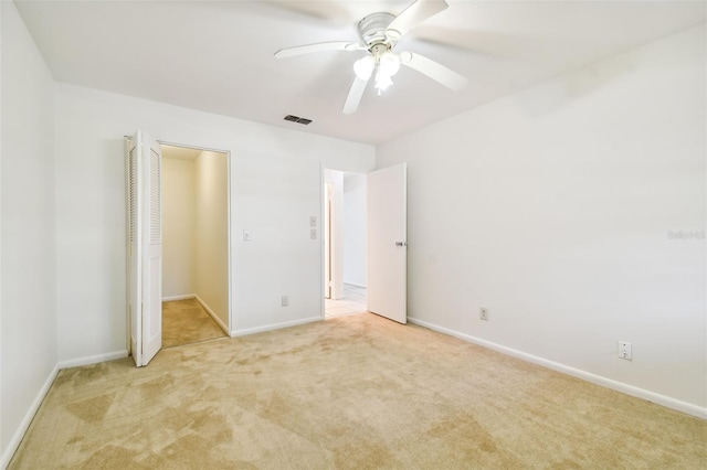 unfurnished bedroom featuring ceiling fan, light colored carpet, and a closet