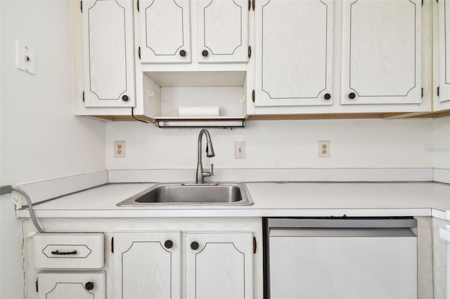 kitchen with sink, dishwashing machine, and white cabinets