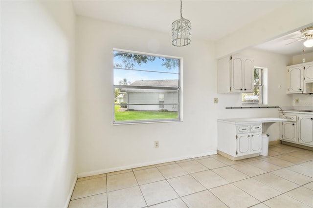 kitchen with decorative light fixtures, light tile patterned flooring, ceiling fan with notable chandelier, and white cabinetry