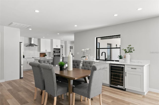 dining space with sink, beverage cooler, and light hardwood / wood-style flooring