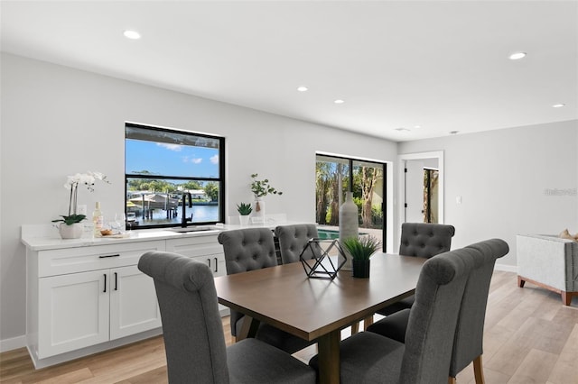 dining room featuring sink, light wood-type flooring, and a water view