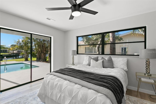 bedroom with light hardwood / wood-style floors, ceiling fan, a water view, and access to outside