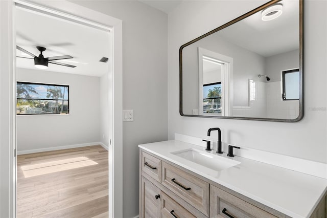 bathroom featuring wood-type flooring, a healthy amount of sunlight, ceiling fan, and vanity