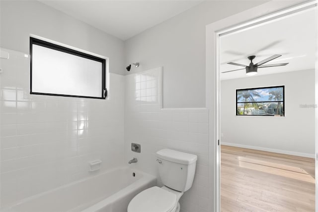 bathroom with ceiling fan, tile walls, tiled shower / bath combo, and toilet