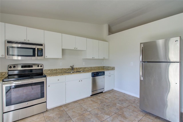 kitchen featuring light stone countertops, appliances with stainless steel finishes, white cabinetry, sink, and lofted ceiling