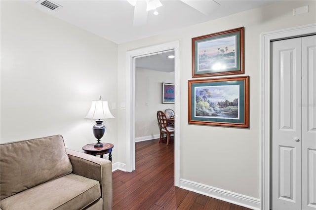 sitting room with dark wood-type flooring and ceiling fan