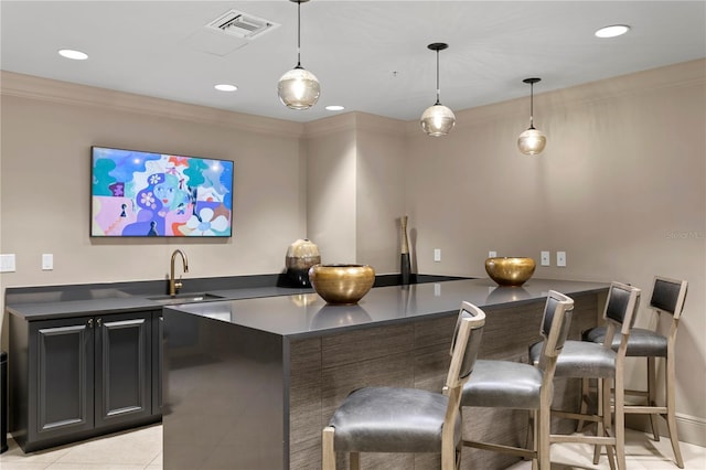 bar featuring hanging light fixtures, crown molding, sink, and light tile patterned floors