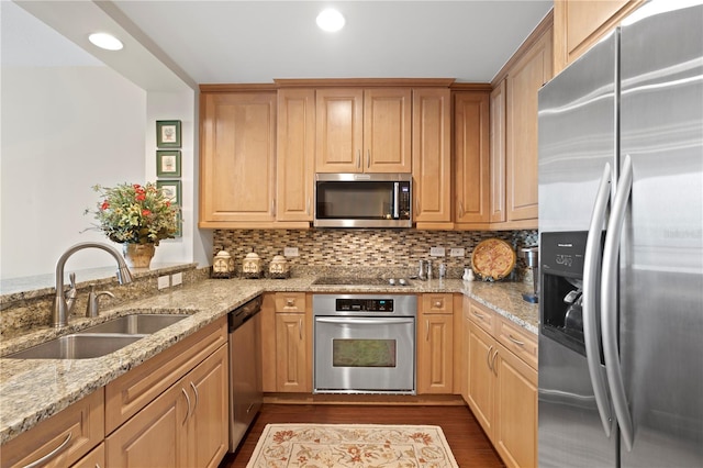 kitchen with sink, appliances with stainless steel finishes, backsplash, light stone counters, and dark hardwood / wood-style flooring