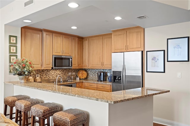 kitchen with stainless steel appliances, light stone countertops, backsplash, and kitchen peninsula