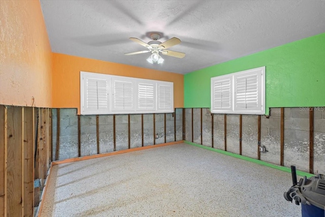 empty room with ceiling fan and a textured ceiling