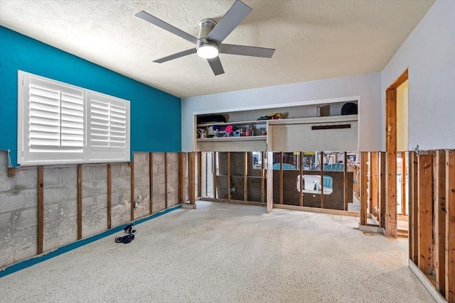 interior space with a textured ceiling and ceiling fan