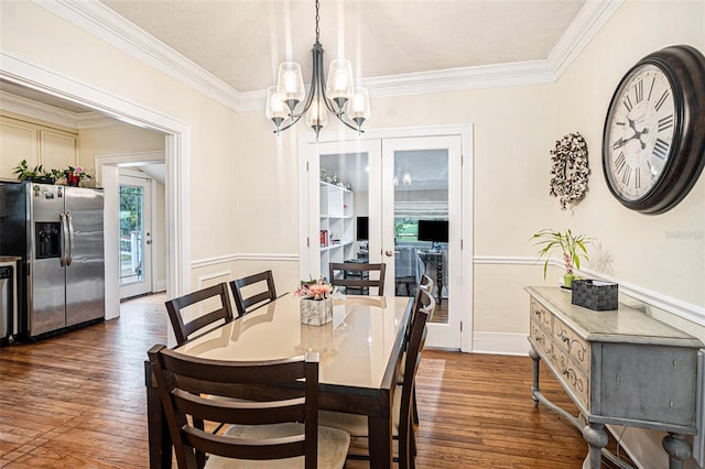 dining area featuring dark wood-type flooring, ornamental molding, and a chandelier