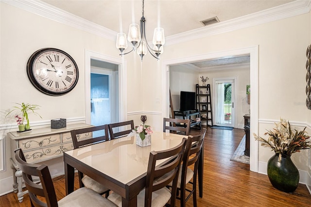 dining space featuring dark wood-type flooring, crown molding, and a notable chandelier