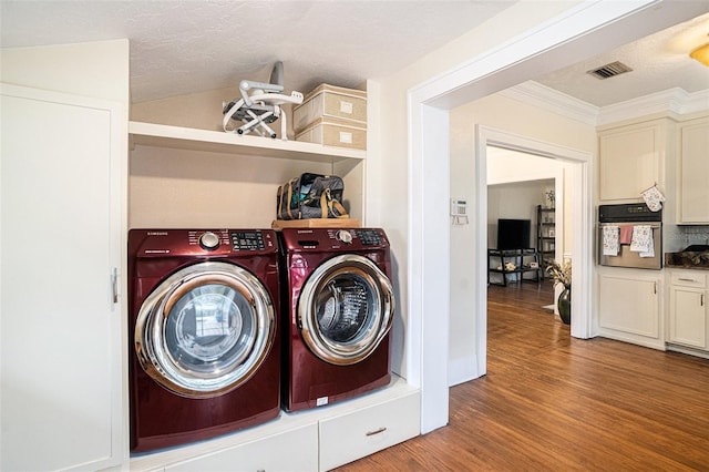 clothes washing area featuring washer and clothes dryer, ornamental molding, a textured ceiling, and light wood-type flooring