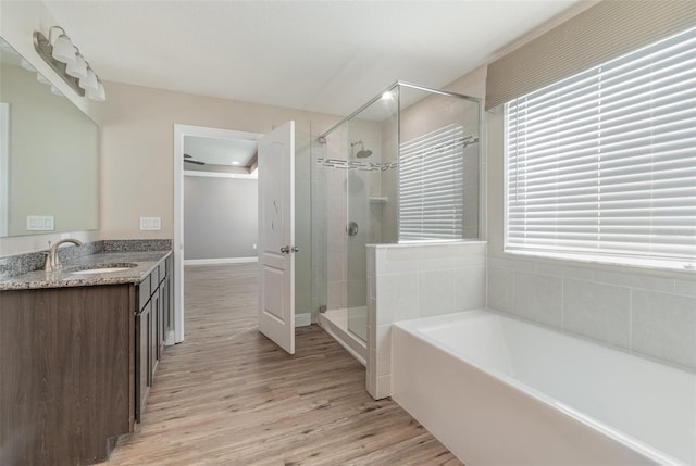 bathroom with hardwood / wood-style flooring, vanity, and plus walk in shower