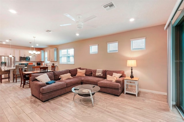 living room featuring ceiling fan with notable chandelier and light wood-type flooring