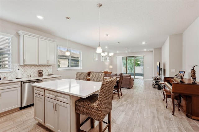 kitchen featuring pendant lighting, dishwasher, white cabinetry, a kitchen island, and a kitchen bar