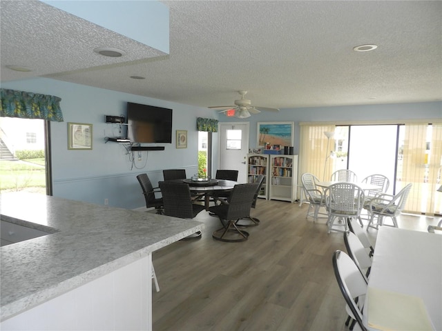 dining area with hardwood / wood-style flooring, ceiling fan, and a textured ceiling