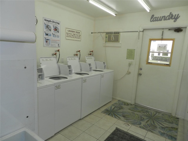 laundry room with an AC wall unit, washer and clothes dryer, and light tile patterned floors