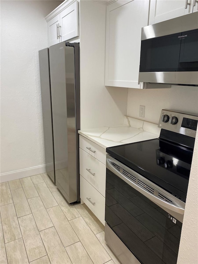 kitchen with light stone counters, white cabinets, and stainless steel appliances